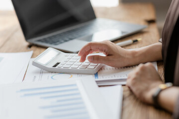 Close-up shot of businesswoman using calculator and laptop to calculate company financial result On...