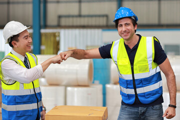 Two technician engineer man in protective uniform with hardhat standing and shaking hands celebrate successful together or completed deal commitment at industry warehouse manufacturing factory