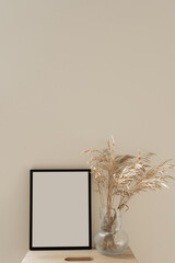 Photo frame with blank copy space on table with dried grass bouquet. Minimal boho styled interior design mockup template