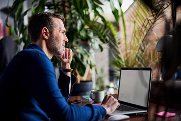 Thoughtful freelancer with laptop at loft office