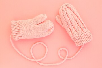 Close-up pink mittens and shaped of string on pink background. Lifestyle and warm feelings concept. Valentine day. Monocolor romantic pattern. Winter theme. Flat lay composition. Top view. Copy space