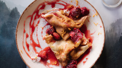 Top view of homemade crepes, tasty thin pancakes with strawberry jam on wooden table