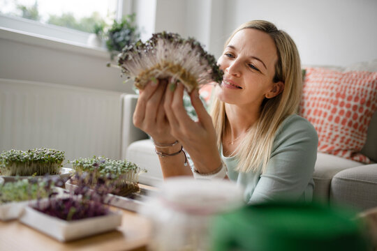 Happy woman looking at sprouts at home