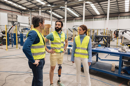 Engineer with artificial limp standing with colleagues in office