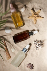 Three summer sunscreen essence on the sand backgroundwith shells ans seastar.
