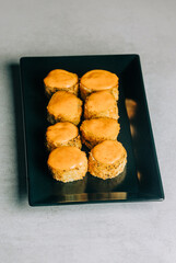 Warm sushi rolls in dried breadcrumbs with mustard on black plate on gray background