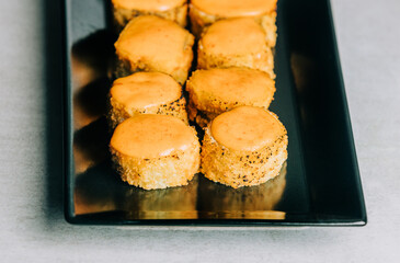 Warm sushi rolls in dried breadcrumbs with mustard on black plate on gray background