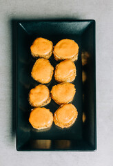 Warm sushi rolls in dried breadcrumbs with mustard on black plate on gray background