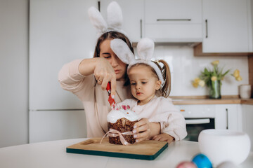 Obraz na płótnie Canvas Little girl with her mother preparing Easter cake in kitchen