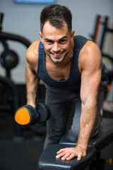 Fototapeta na wymiar happy man doing exercise with a dumbbell in gym