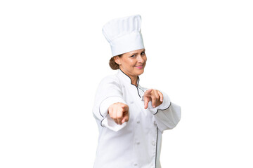 Middle-aged chef woman over isolated background points finger at you while smiling