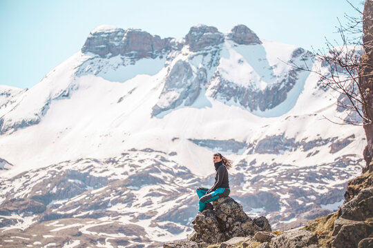 Hiker sitting on rock in front of snowy mountains