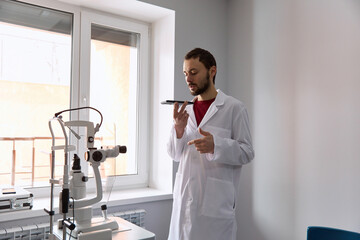 Doctor talking on speaker phone standing in clinic