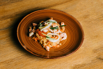 Rice with seafood, calmari and cucumber on brown plate