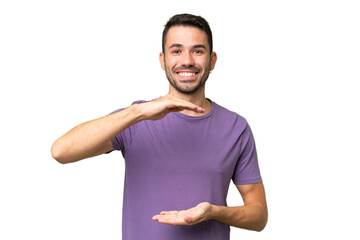 Young handsome caucasian man over isolated background holding copyspace imaginary on the palm to...