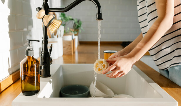 Girl washing loofah in sink at home