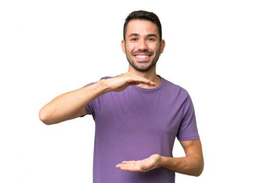 Young handsome caucasian man over isolated background holding copyspace imaginary on the palm to insert an ad