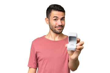 Young handsome caucasian man holding a engagement ring over isolated background with happy expression