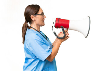 Middle-aged nurse woman over isolated background shouting through a megaphone