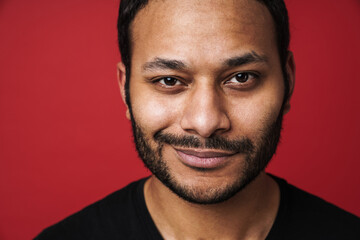 Indian man looking at camera and smiling isolated over red background