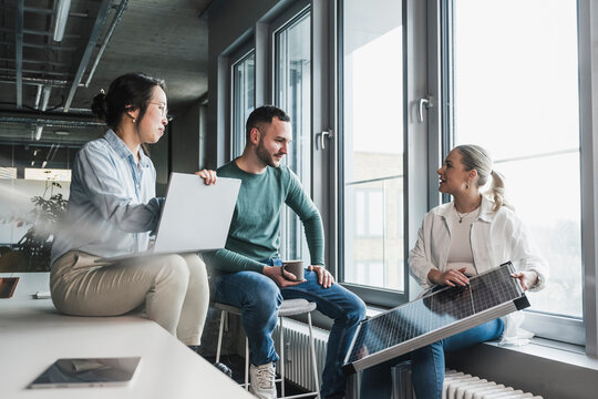 Businesswoman explaining solar panel to multiracial colleagues in meeting at office