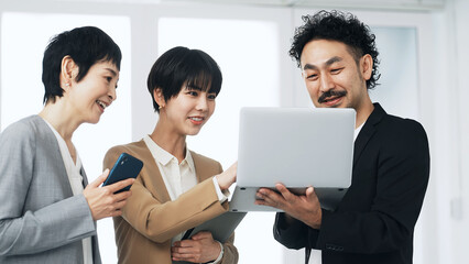 パソコンを見ながら話すビジネスパーソンのグループ