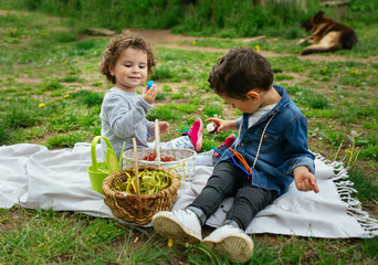Boy and girl on picnic, eating eggs from Easter egg hunt