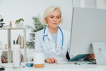 Mature doctor working on desktop PC at desk