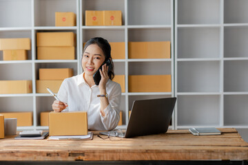 Startup, small business, SME, Asian female entrepreneur owner uses smartphones to talk to customers online and check online orders to prepare packages. Sell Ideas Online.