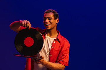 African man posing with vinyl records isolated over blue background