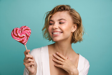 Cheerful woman posing with lollipop isolated over blue background
