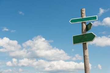 Green signpost with blue sky and white clouds in background
