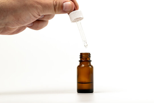Closeup photo of person dispensing medical drops - vertically dripping into a brown bottle by a spuit