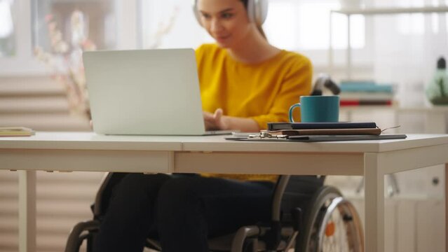 Young woman with disability listening to music and playing video game on laptop