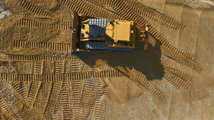 yellow bulldozer working on flat area, top view