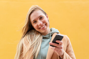 Young blonde woman at outdoors using mobile phone