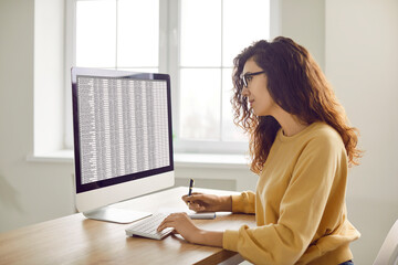 Female accountant working with digital business spreadsheets on office computer. Young woman in...