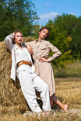 Naklejka na ściany i meble Full length portrait two young stylish girls posing in the hayloft