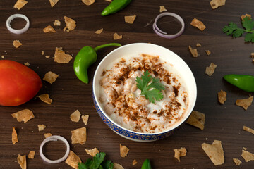 Dahi vada or bhalla is a type of chaat originating from the Indian and popular throughout South Asia. Dahi bhalla bowl on textured background. 