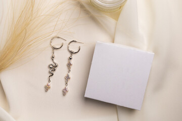 Fototapeta na wymiar Elegant jewelry set of silver earrings with gem and gift box mock up copy space. Jewelry set minimalist style. Handmade bijouterie concept.