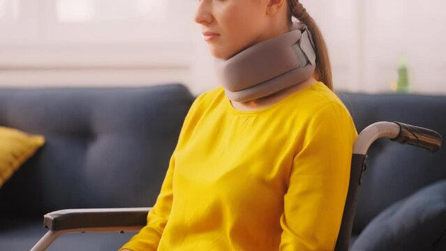 Pensive young woman with neck collar brace sitting in wheelchair, rehabilitation