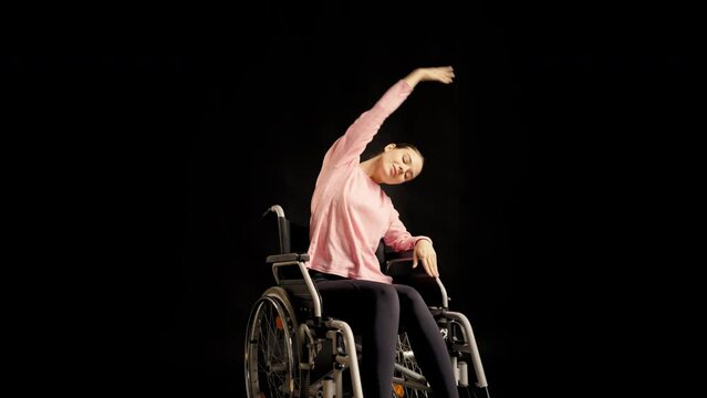 Young woman with disability doing stretching exercise in wheelchair, yoga time