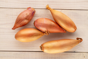 Several organic onions on a wooden table, macro, top view.