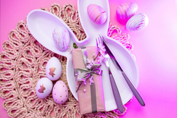 bunny plate with cutlery , easter eggs, gifts with green ribbon, spring sakura flowers on a pastel pink background with neon glow.  Easter composition. copy space. view from above. flat lay