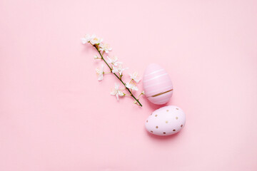 easter eggs with cherry blossom branch on a pastel pink background. copy space. flat lay. top view