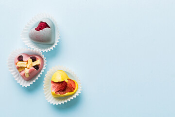 chocolate sweets in the form of a heart with fruits and nuts on a colored background. top view with space for text, holiday concept