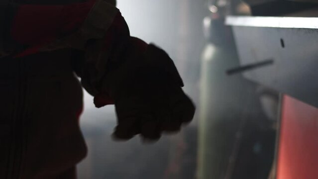 A blacksmith puts their gloves on atop a welding machine in a workshop