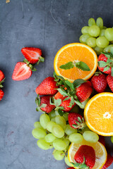Various fruits and berries on dark gray background in the kitchen