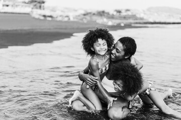 African sister twins having fun with mother on the beach - Focus on mom face - Black and white editing