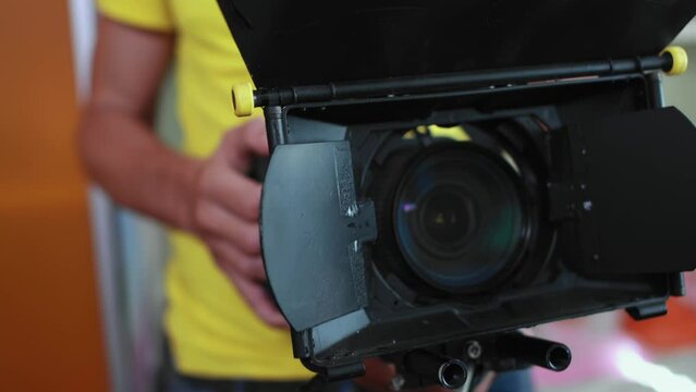 Cameraman operator holds cinema camera in hands, lens with matte box. Backstage filming of movie indoors. Cinematography. Production of commercial ad or TV series. DOP is on set scene. Videography